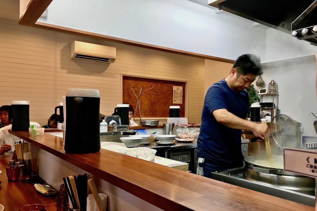 Watching him make ramen at the counter in Daruma