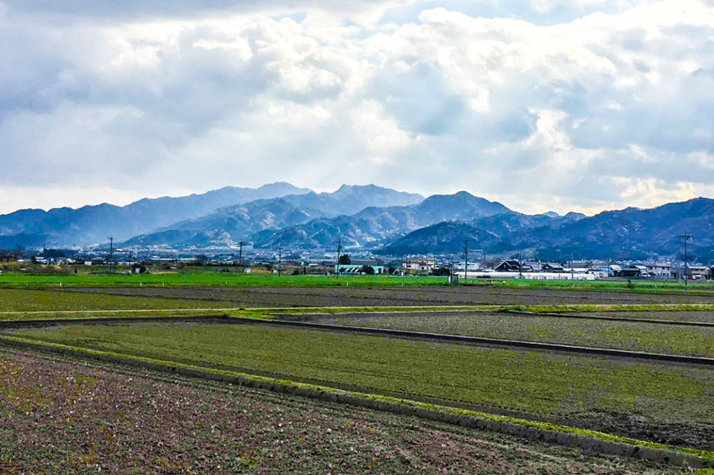 Open fields surrounded by mountain ranges characterize much of the Honshu landscape.