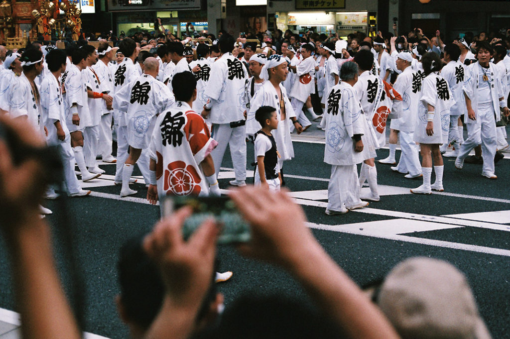 Gion Matsuri envelopes and absorbs Kyoto's famous 'Shijo' - Fourth Avenue. Men in 'happi' coats swirl like storm clouds around Mikoshi and Yamahoko.