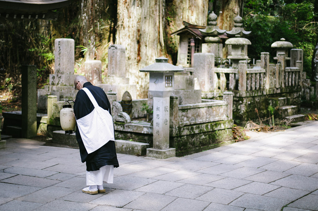 A Buddhist monk bows in prayer at a small altar on the central pathway of Okuno-in, Kōya-san.