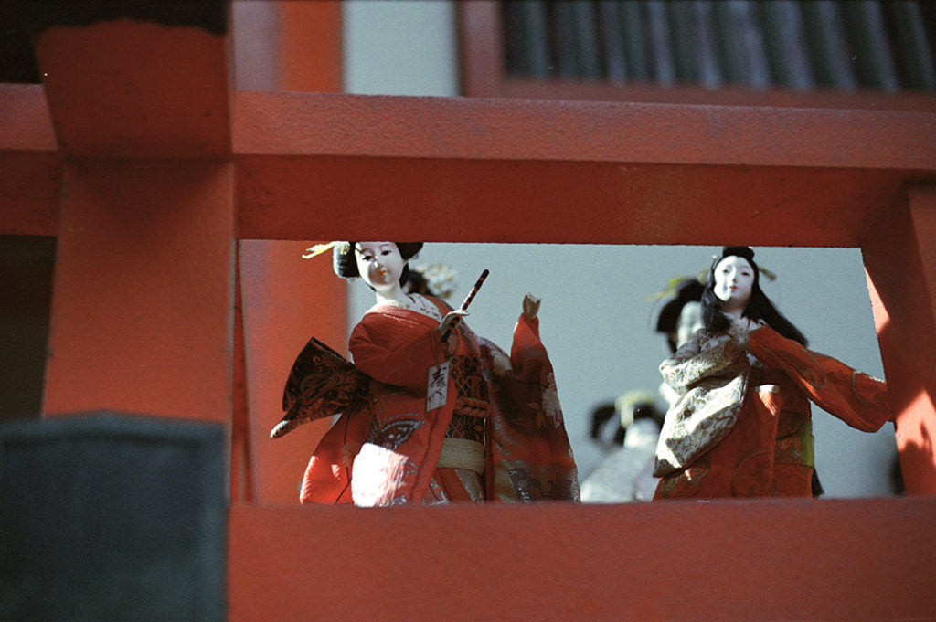 Figurines watch silently from the vibrant red balconies.