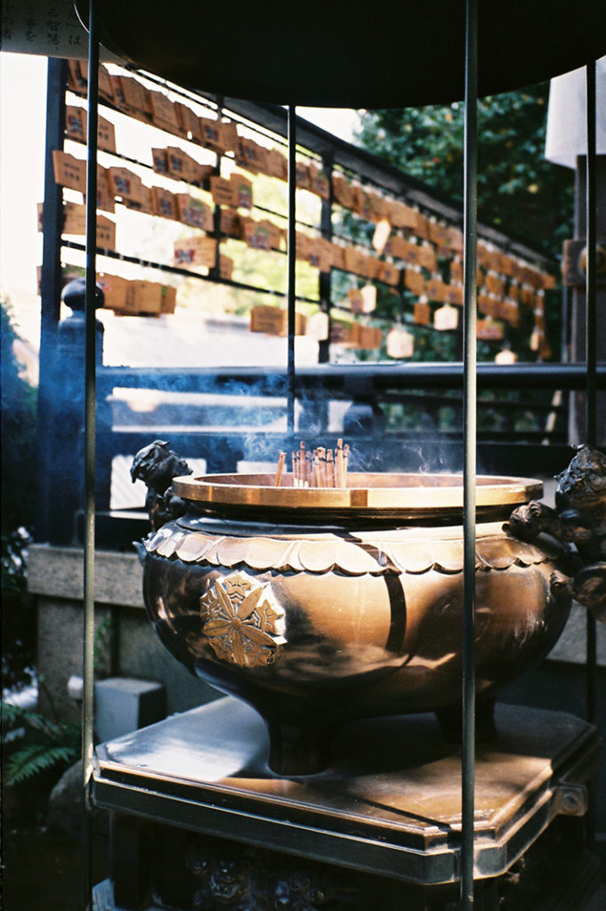 Thick incense sticks billow out blue-tinged smoke at the entrance to Hozan-ji's prayer hall.