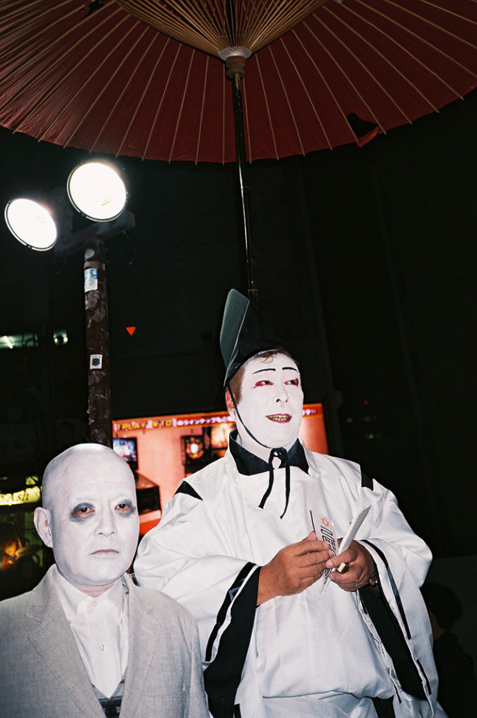 A uniquely Japanese pair of costumers attend an outdoor event in Osaka, Japan. 4 points!