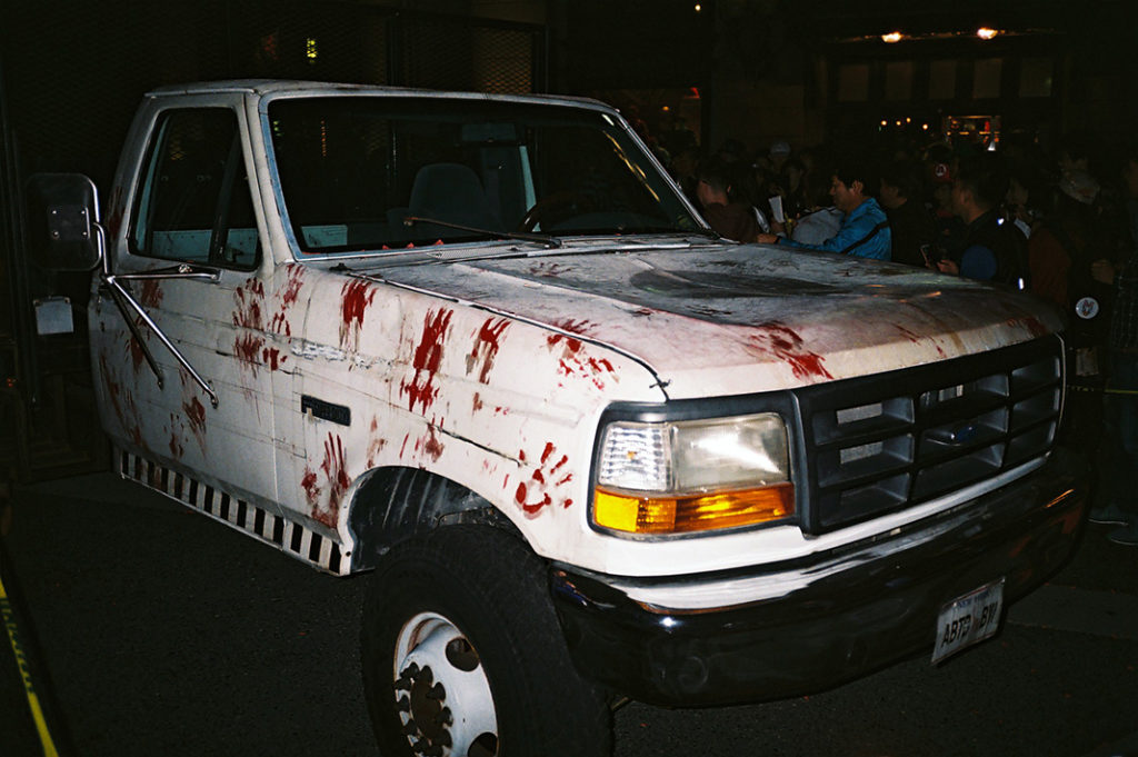 A pickup truck is covered in bloody handprints at a Halloween event. 2 points!
